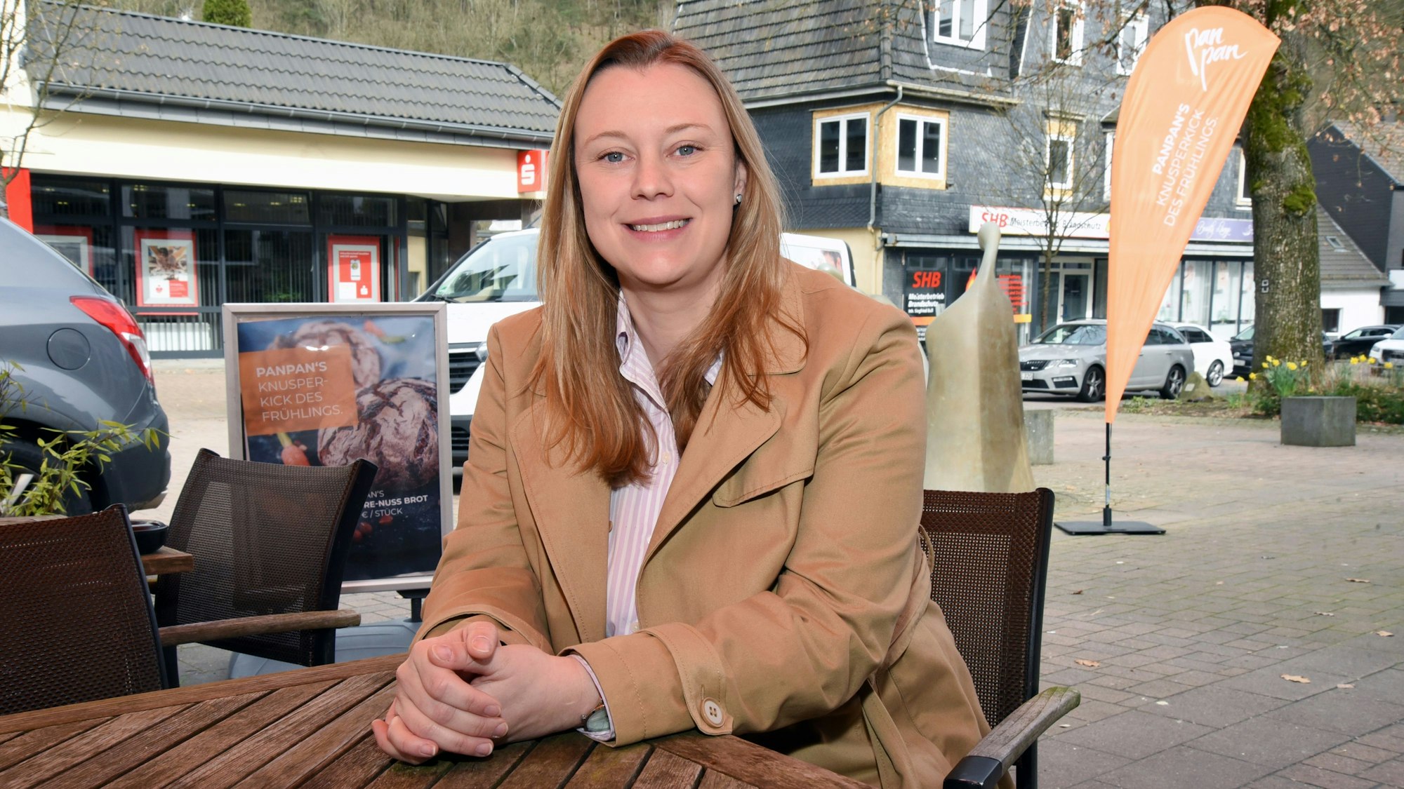 Eine junge Frau sitzt an einem Tisch vor der Bäckerei in Bielstein.