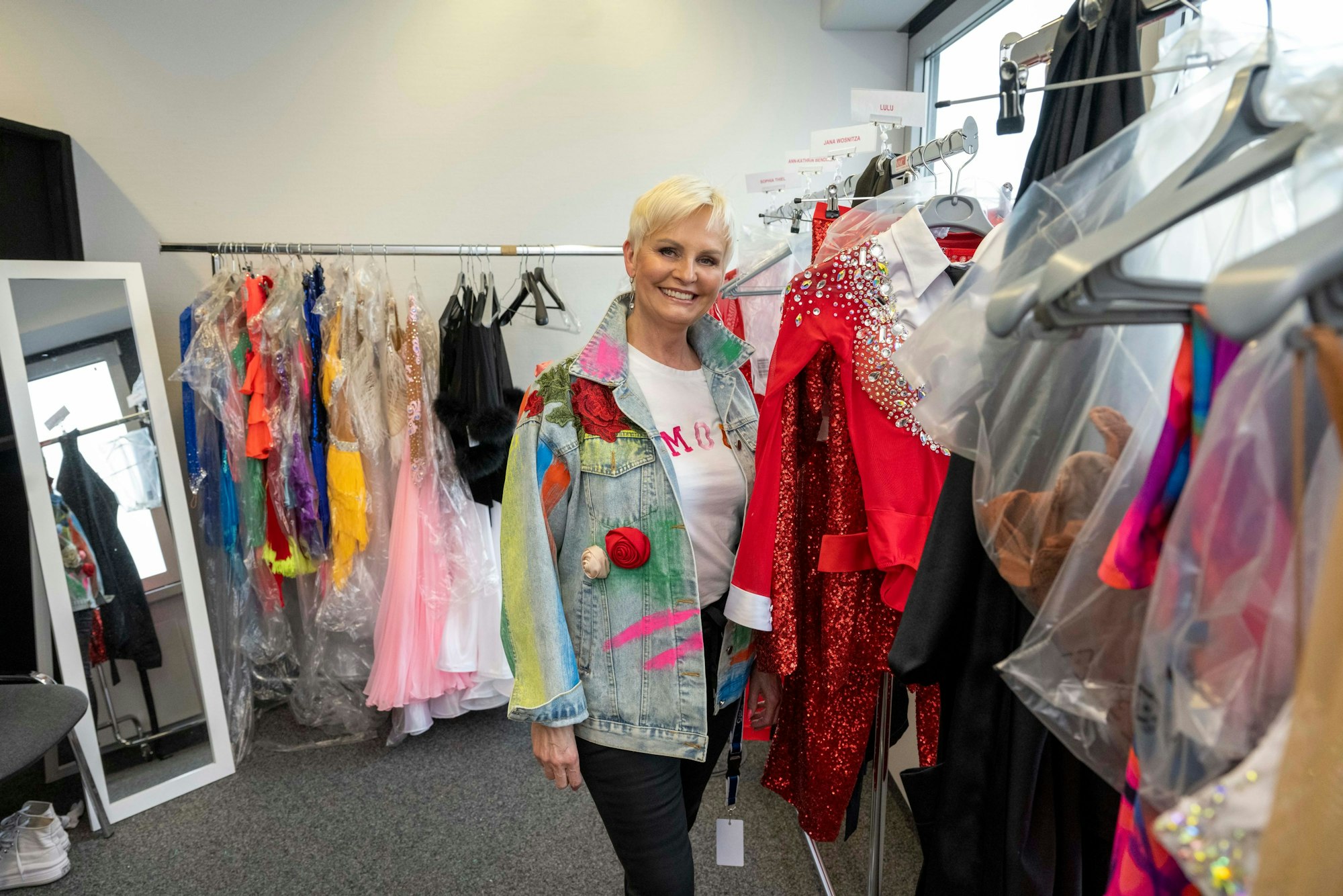 Katia Convents steht neben einer Kleiderstange voller Tanzkleider.