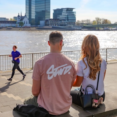 Ein Paar sitzt bei schönem Wetter am Kölner Rheinufer. Am Samstag erreichten die Temperaturen in Köln und der Region mehr als 25 Grad.