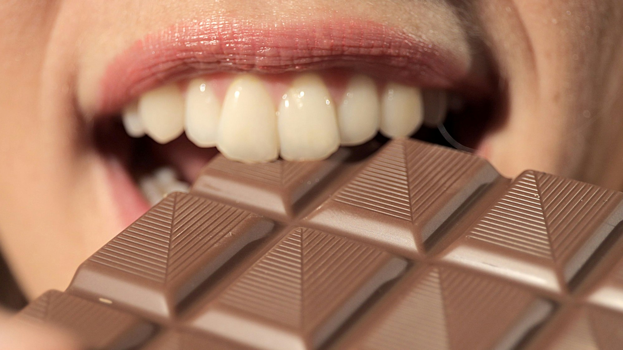 Eine Frau beißt in eine Tafel Schokolade.