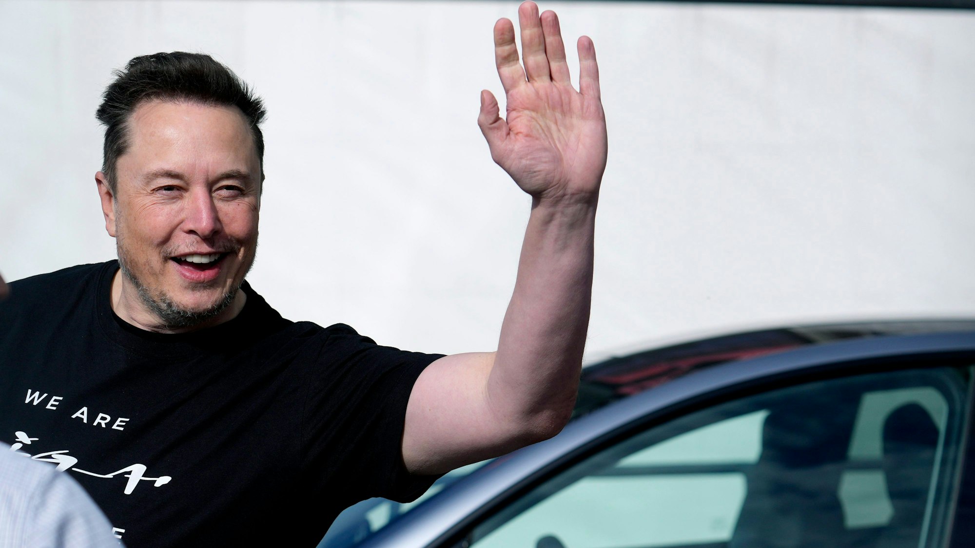 Elon Musk, Tesla-Chef, winkt in eine Kamera.