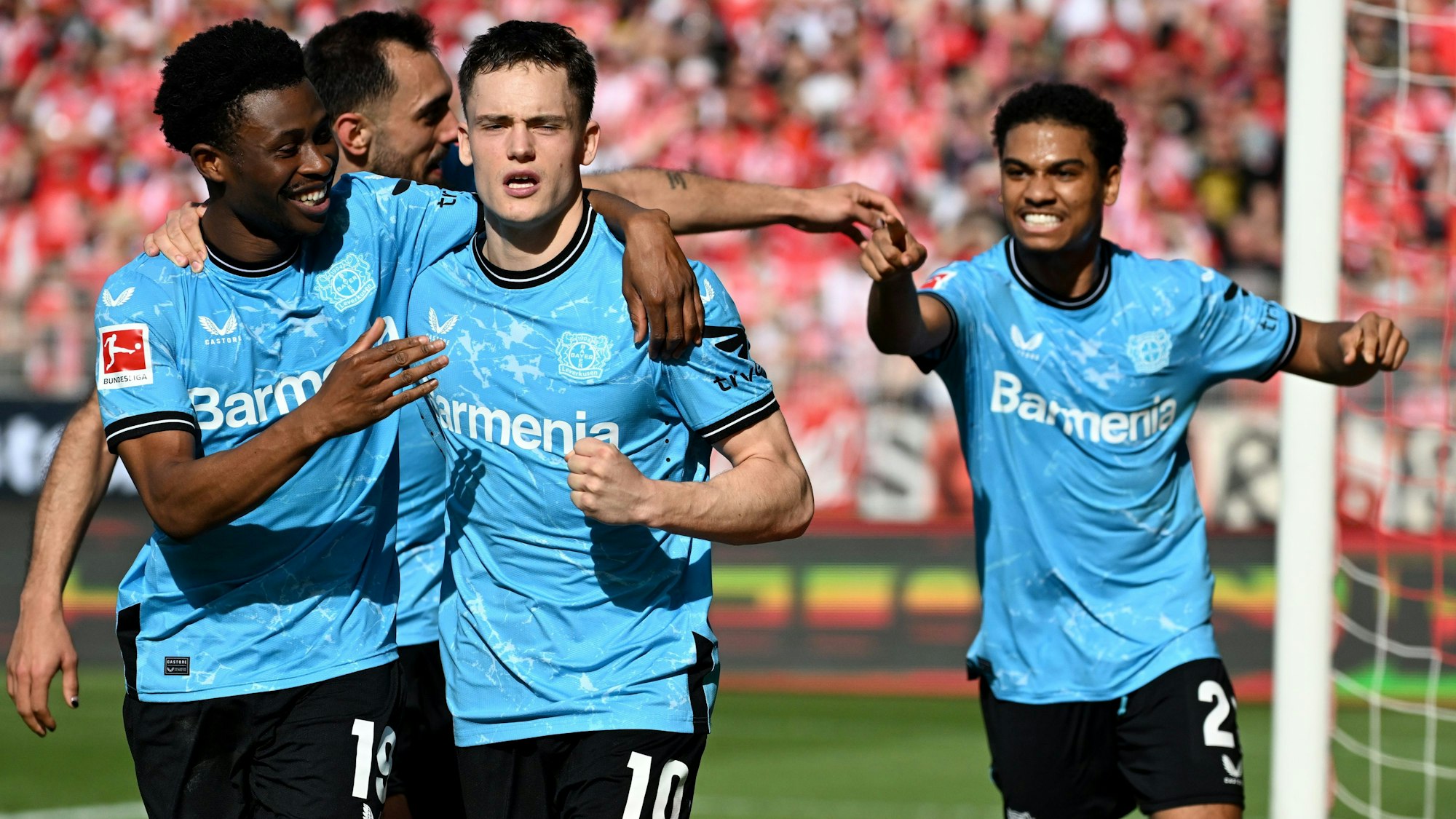 03.04.2024, Berlin: Fußball: Bundesliga, 1. FC Union Berlin - Bayer Leverkusen, 28. Spieltag, An der Alten Försterei. Florian Wirtz (M) von Bayer Leverkusen bejubelt sein Tor zum 1:0 mit Nathan Tella (l) und Amine Adli. Foto: Britta Pedersen/dpa - WICHTIGER HINWEIS: Gemäß den Vorgaben der DFL Deutsche Fußball Liga bzw. des DFB Deutscher Fußball-Bund ist es untersagt, in dem Stadion und/oder vom Spiel angefertigte Fotoaufnahmen in Form von Sequenzbildern und/oder videoähnlichen Fotostrecken zu verwerten bzw. verwerten zu lassen. +++ dpa-Bildfunk +++
