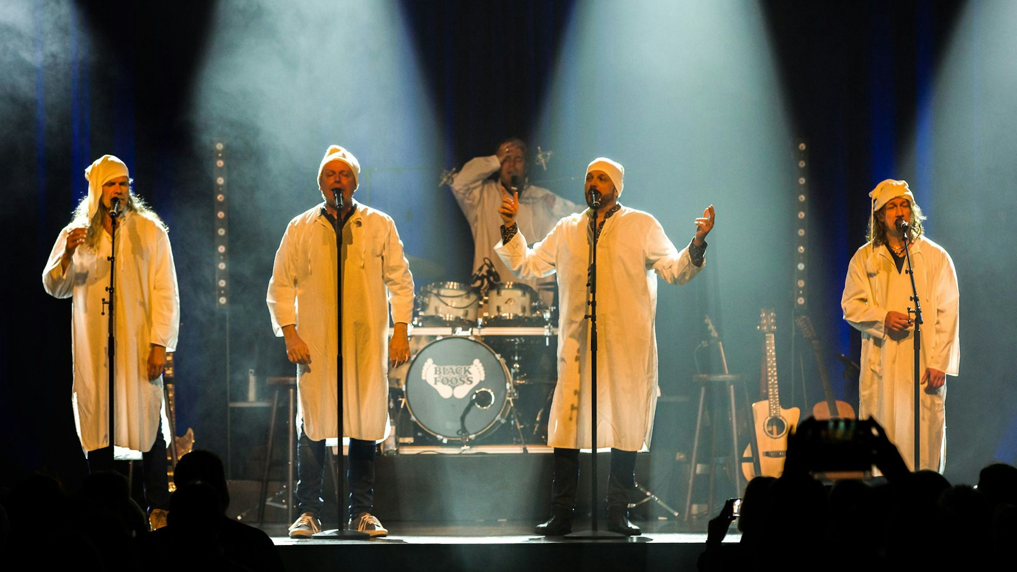 Sänger stehen in Schlafgewändern und Zipfelmützen auf der Bühne.