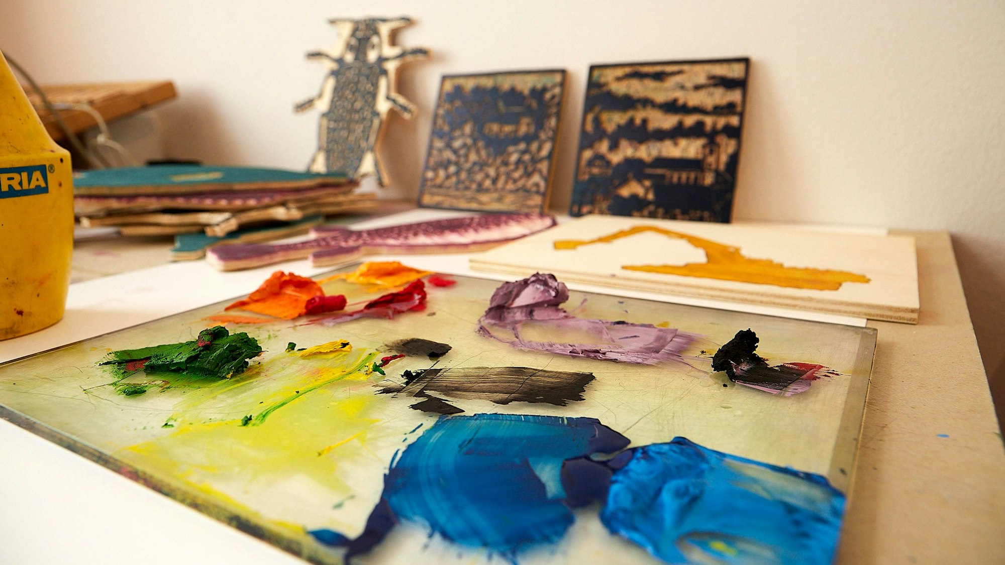 Ein kleines Druckatelier: Auf einem Tiisch liegen farbige Probedrucke.