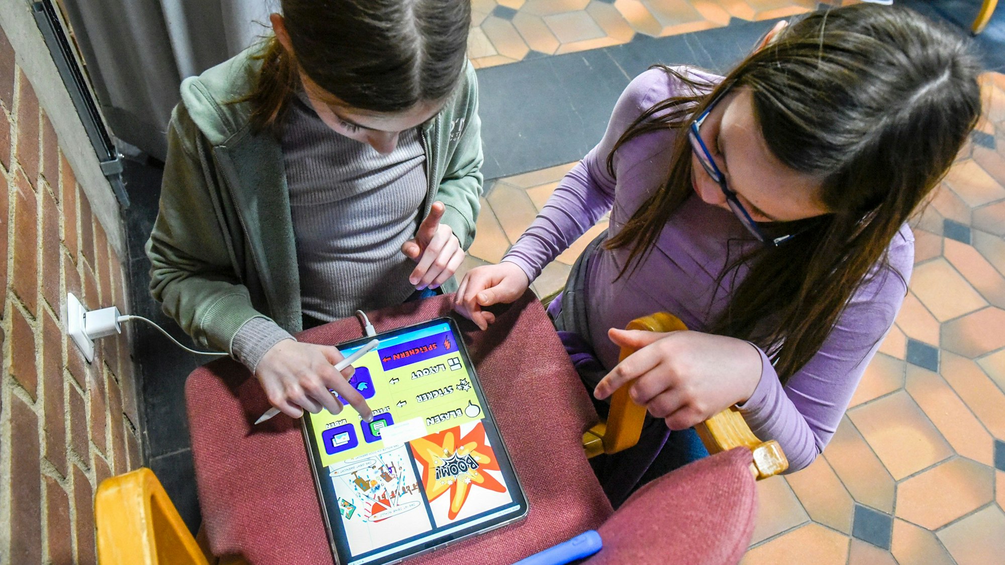 Zu sehen sind zwei Kinder, die am Tablet-PC einen Comic erstellen.