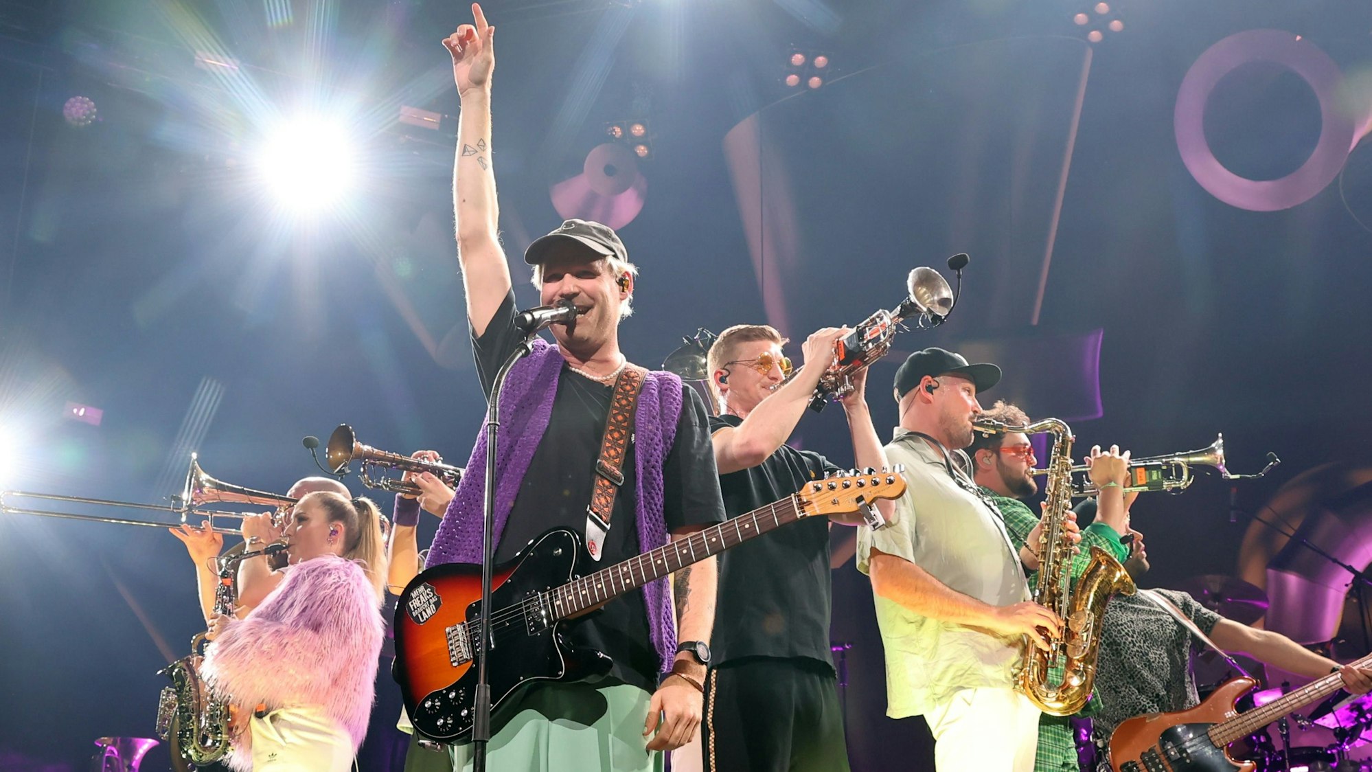 Mehrere Mitglieder der Brasspop-Band Querbeat stehen auf der Bühne der Kölner Lanxess Arena.