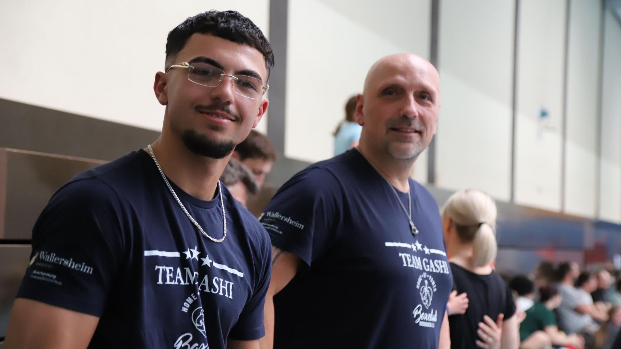 Ein jüngerer und ein älterer Mann mit T-Shirts vom „Team Gashi“.