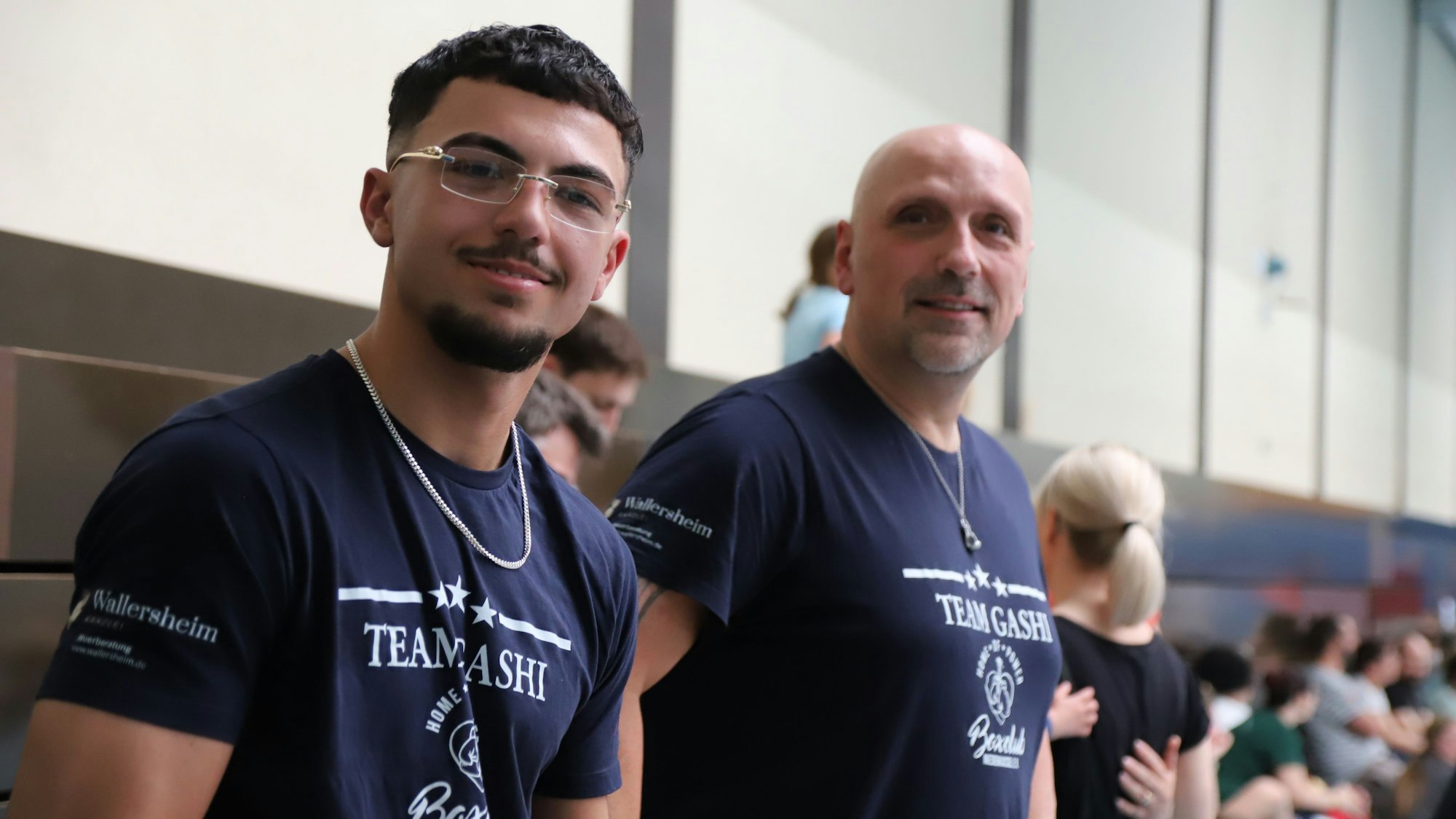 Ein jüngerer und ein älterer Mann mit T-Shirts vom „Team Gashi“.