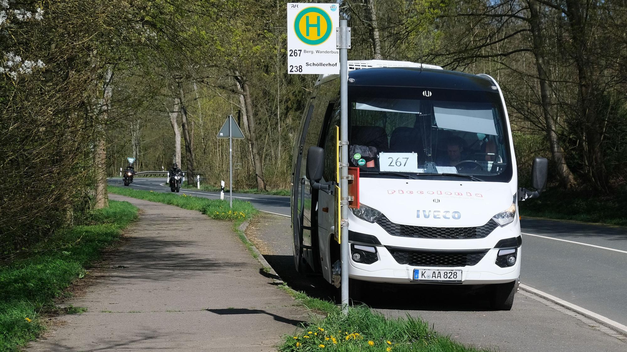 Der weiße Kleinbus steht an einer Haltestelle an einer Landstraße.