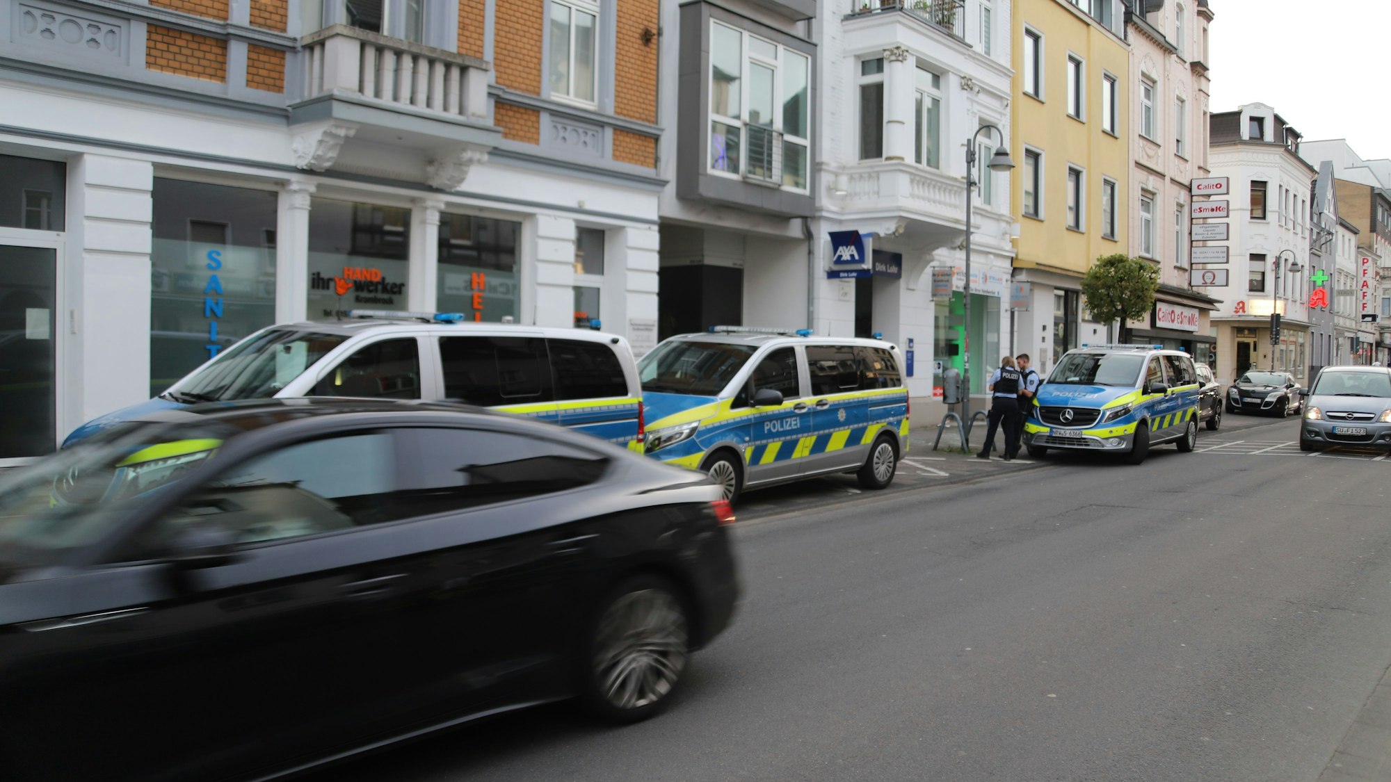 Mehrere Fahrzeuge der Polizei stehen vor einer Häuserzeile.
