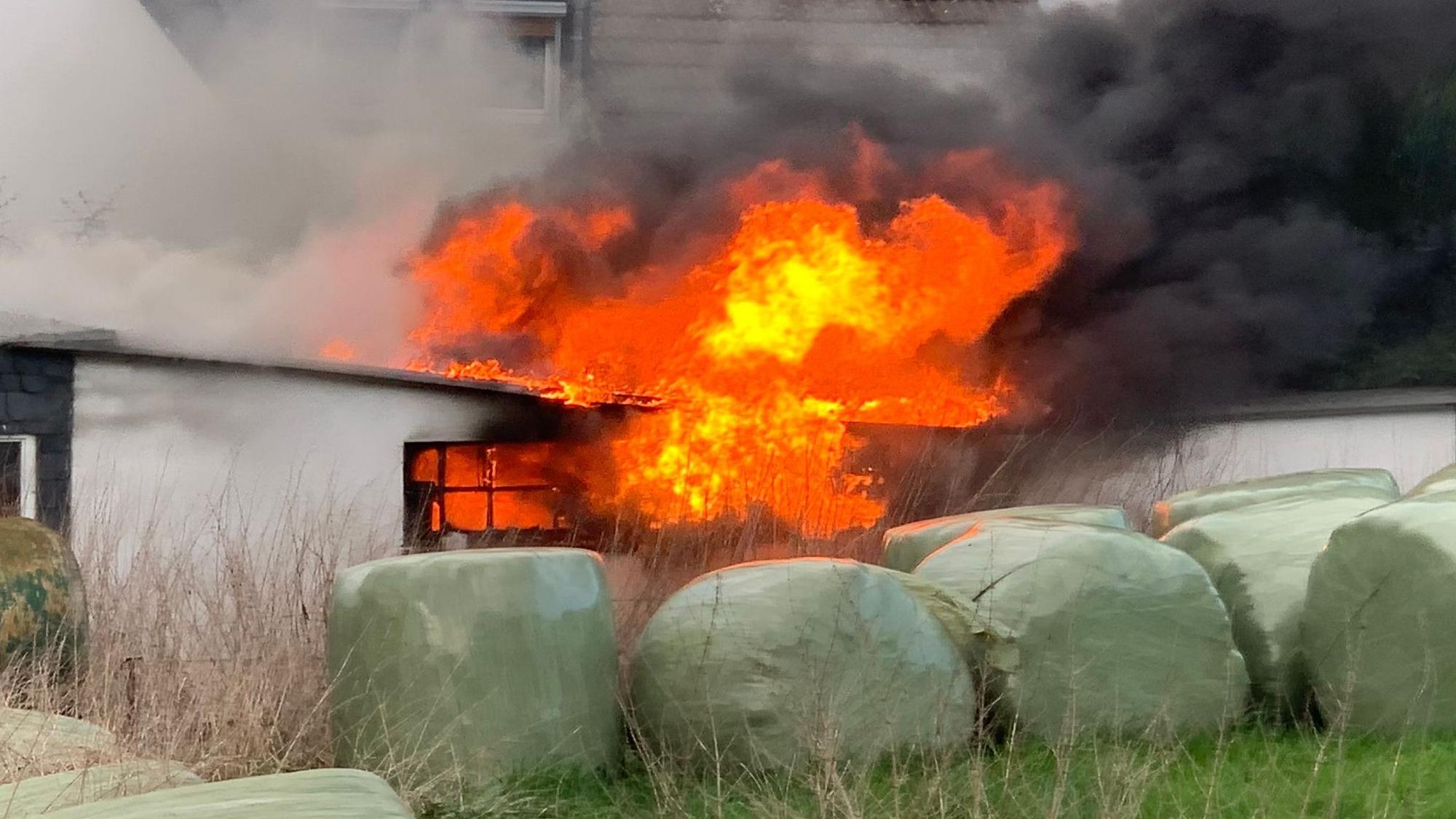 Rot glühende Flammen schlagen aus dem Fenster und dem Dach einer Doppelgarage.
