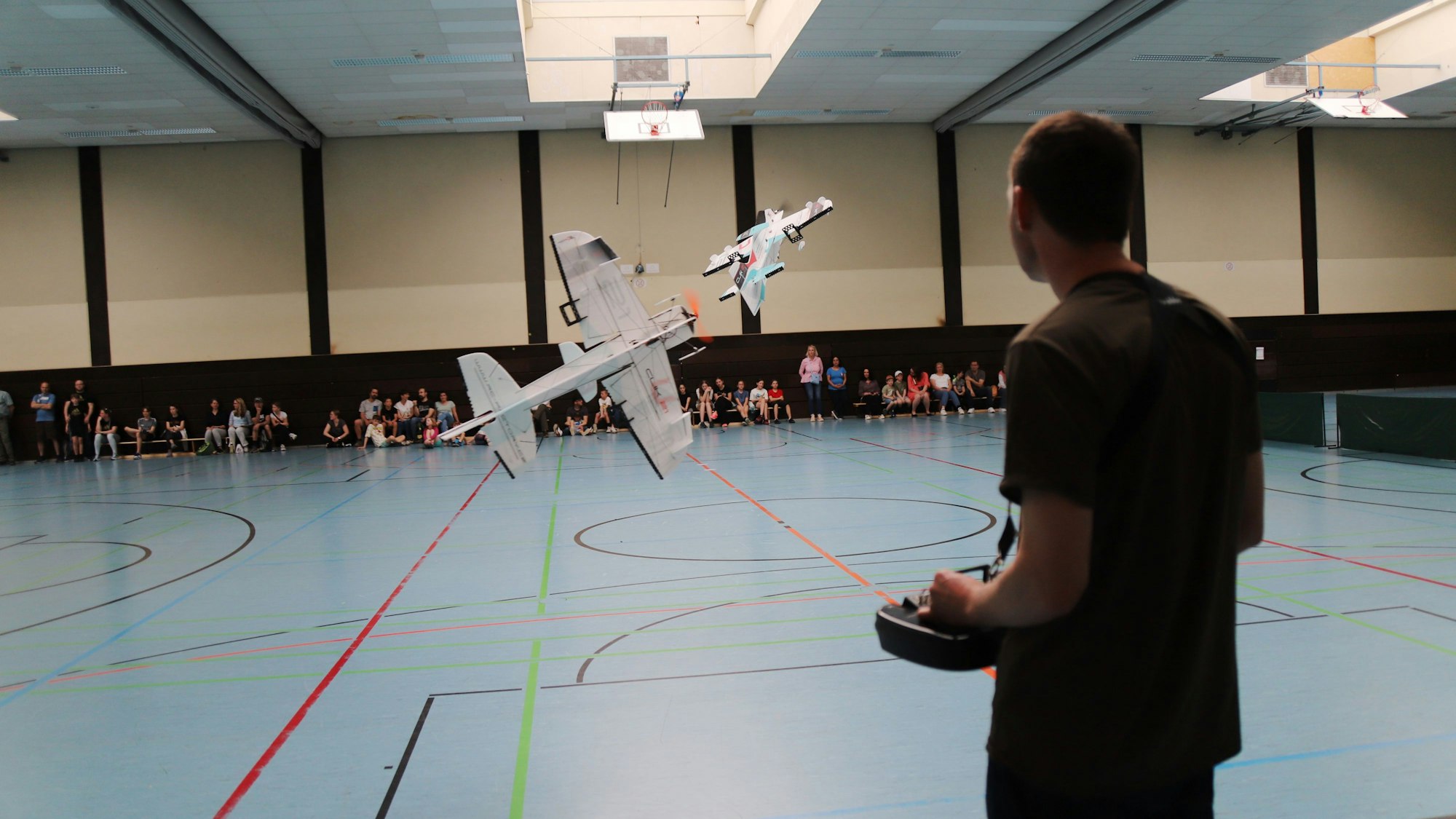 Ein junger Mann steuert ein Modellflugzeug in der Sporthalle im Schulzentrum Niederkassel.