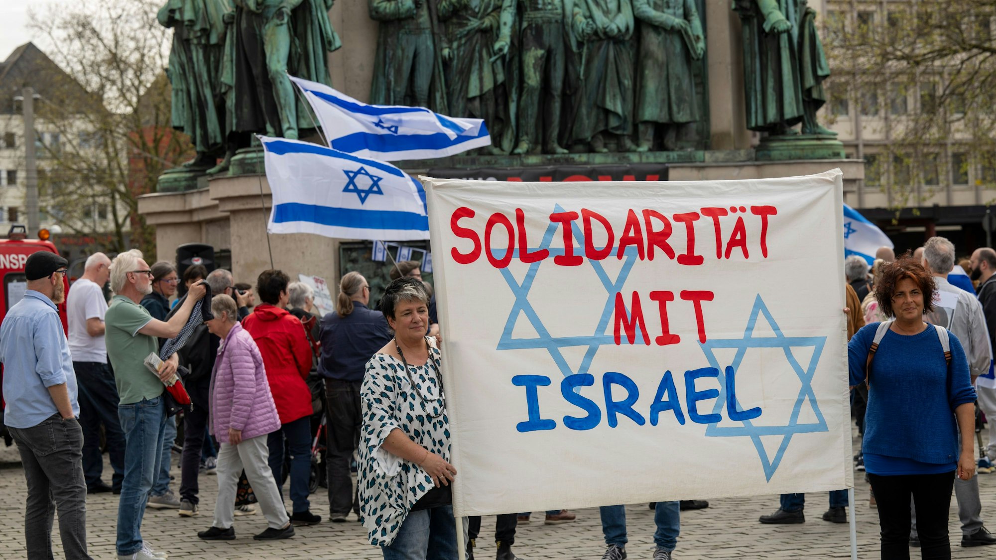Menschen halten ein Banner hoch mit der Aufschrift „Solidarität mit Israel“.