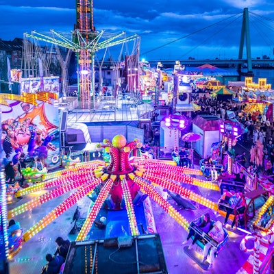 Die Deutzer Kirmes leuchtet in der Abenddämmerung: Im Vorfeld hatte es auch Streitigkeiten um die Stromversorgung gegeben.