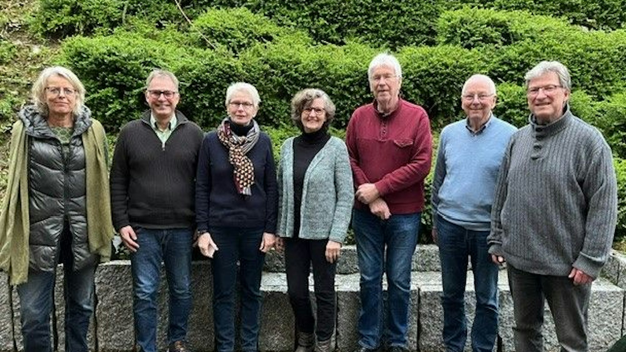 Die Vorstandsmitglieder stehen nebeneinander vor einer kleinen Mauer.