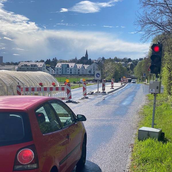 Zu sehen ist ein Auto, das vor der Bedarfsampel steht und dessen Fahrer auf Grünlicht wartet.