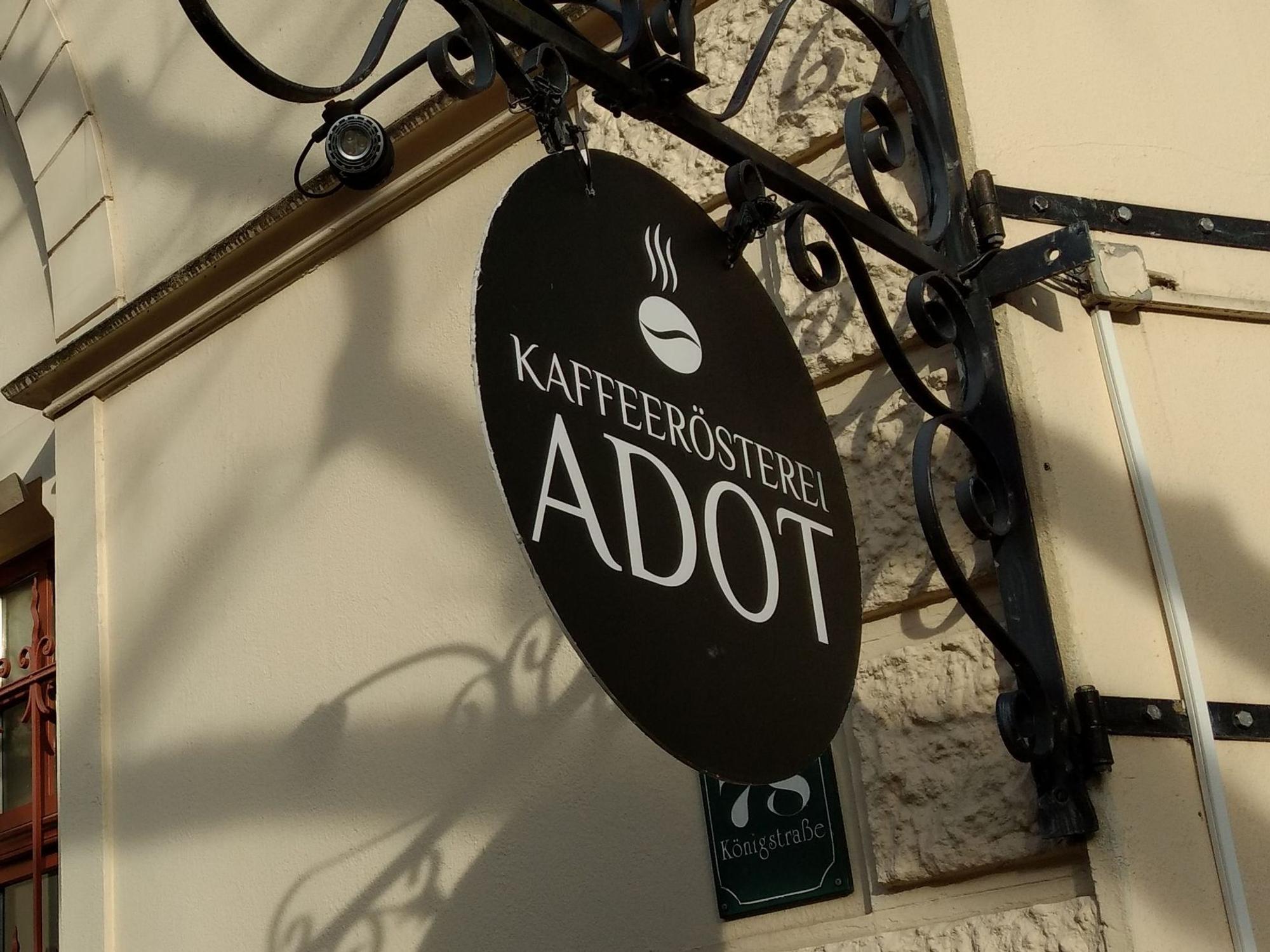 An der Fassade hängt ein Schild mit der Aufschrift „Kaffeerösterei Adot“.