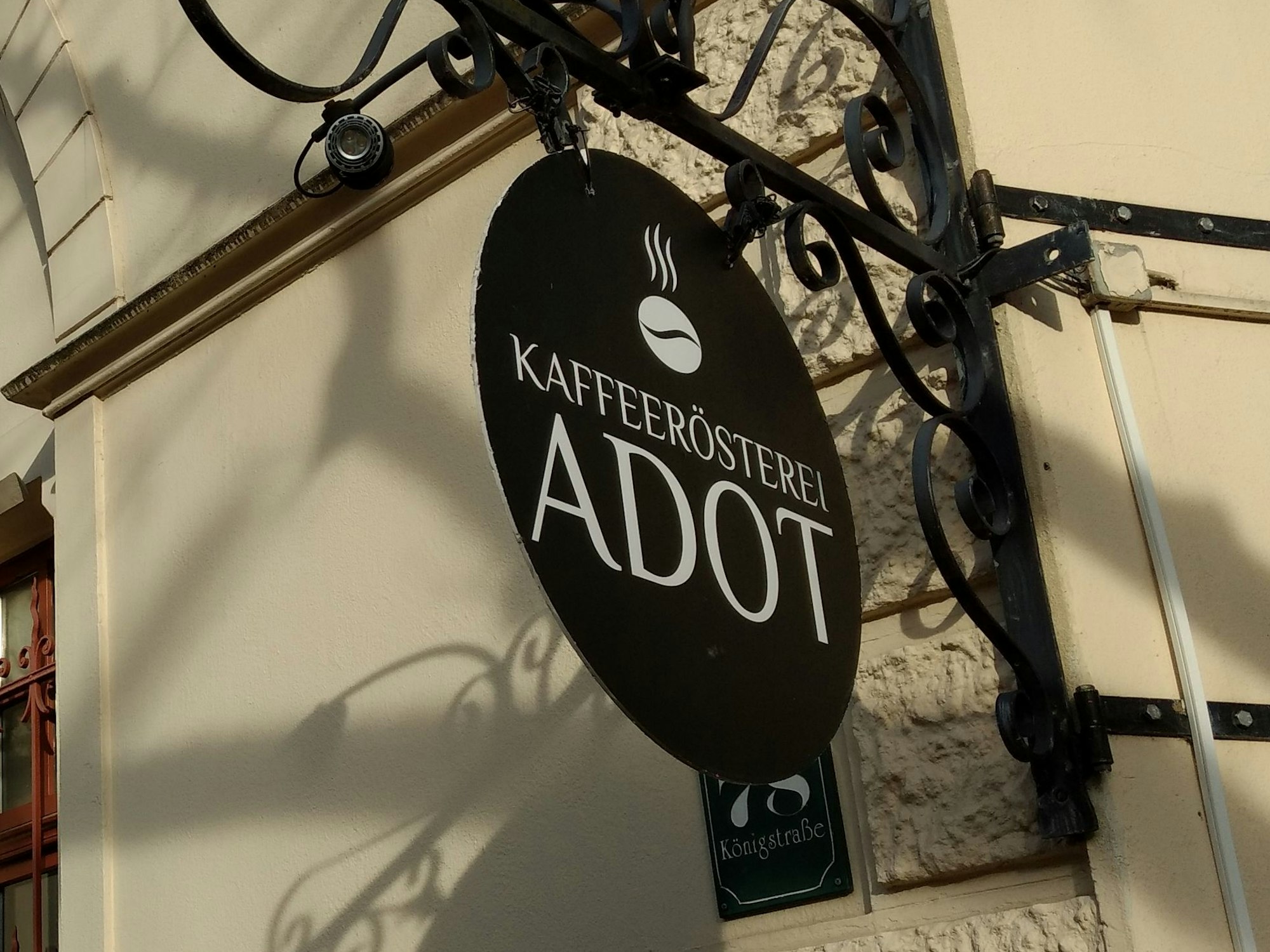 An der Fassade hängt ein Schild mit der Aufschrift „Kaffeerösterei Adot“.