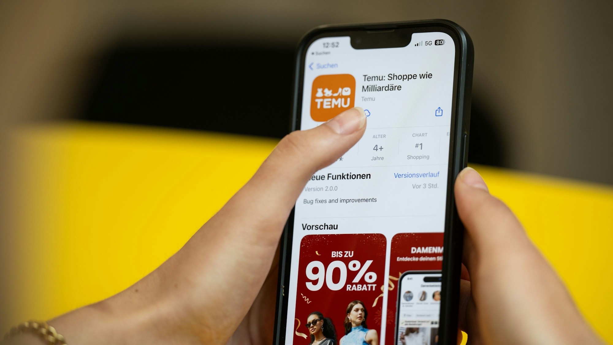Eine Person hält ein Telefon mit der App Temu in den Händen. (Gestellte Szene)