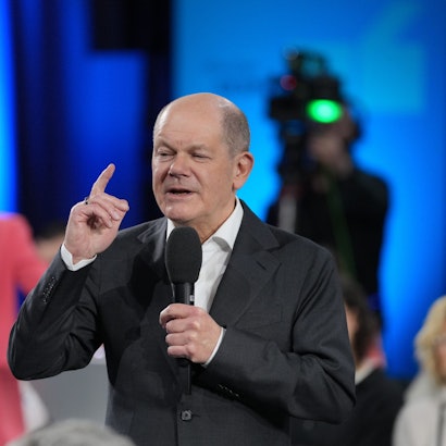 Zu sehen ist Bundeskanzler Olaf Scholz mit einem Mikrofon in der Hand.