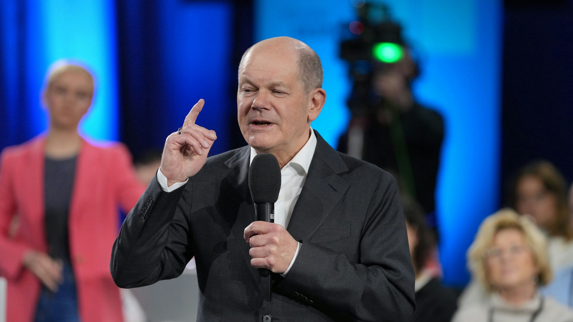 Zu sehen ist Bundeskanzler Olaf Scholz mit einem Mikrofon in der Hand.