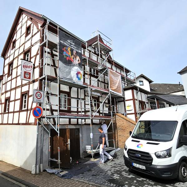 Blick auf das eingerüstete Gasthaus Gier. Mitarbeiter einer Malerfirma sind bei der Arbeit.
