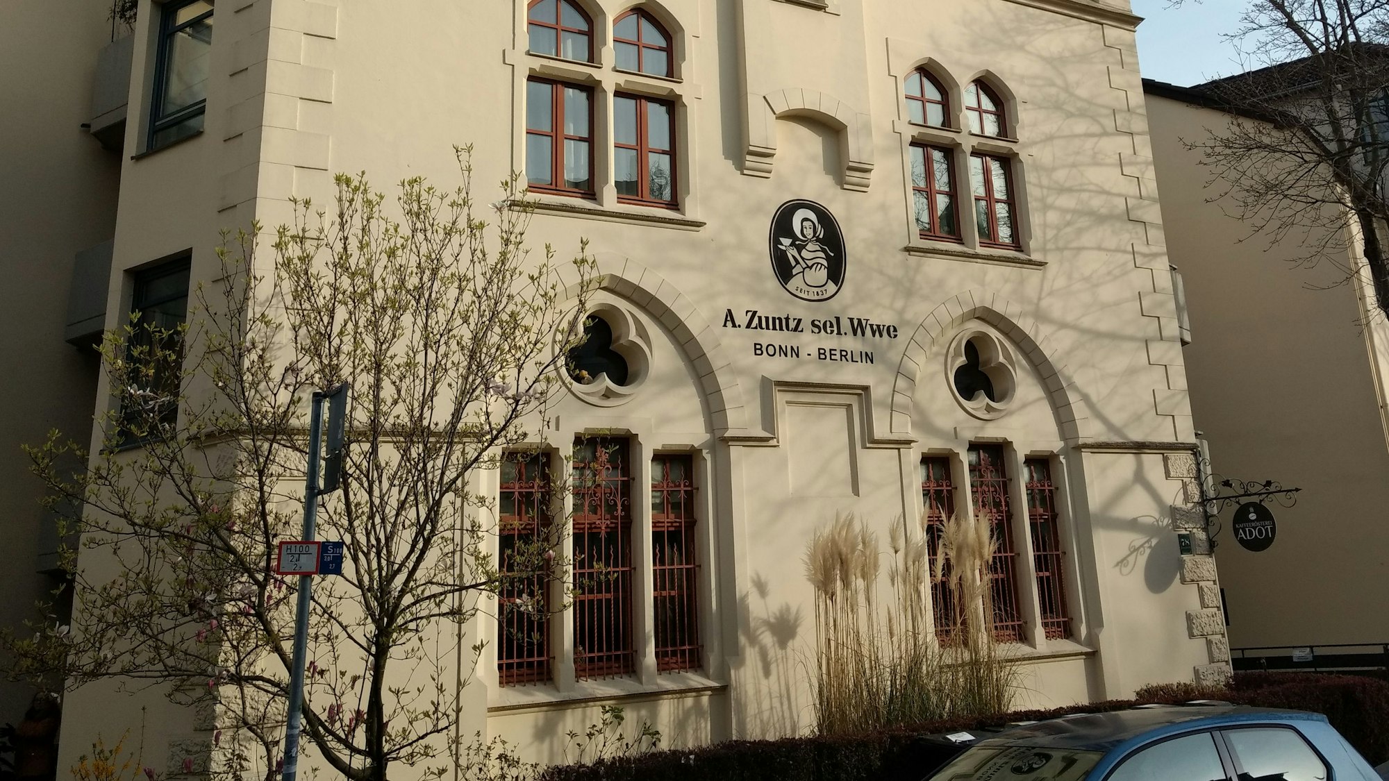 Das Gebäude der ehemaligen Kaffeerösterei in der Bonner Südstadt. Es ist das bekannte Logo zu sehen: Eine Frau mit Kleid und Schutenhut hält eine Kaffeetasse mit Untertasse in der Hand. Darunter die Aufschrift: „A. Zuntz sel. Wwe / Bonn – Berlin“.