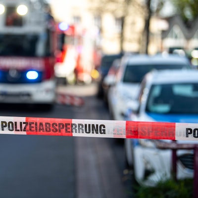 Das Bild zeigt eine Polizeiabsperrung. Im Hintergrund ist ein Feuerwehrfahrzeug zu sehen.
