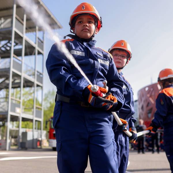 Kinder in Feuerwehruniformen richten den Schlauch auf das Ziel.