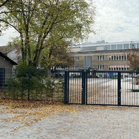 Zu sehen ist der Schulhof der Gemeinschaftsgrundschule Porz-Mitte und Schulgebäude.
