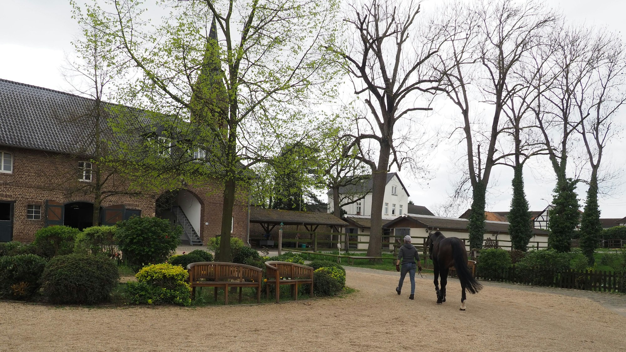 Das Bild zeigt den Innenhof der Burg Müggenhausen mit einigen Gebäuden und Bäumen.