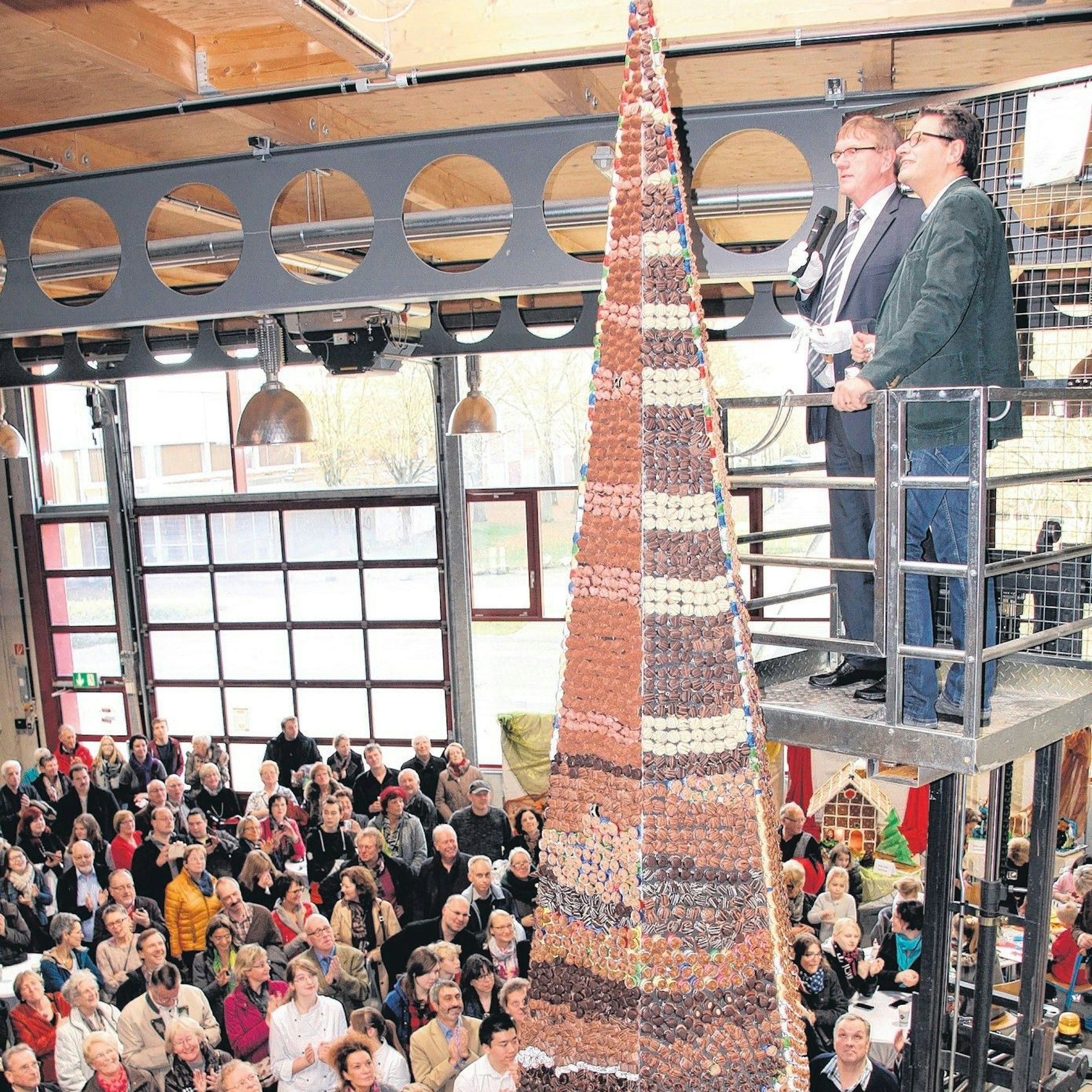 Im Jahr 2014 steht in einer Halle vor Publikum eine sechs Meter hohe Pyramide, die von unten bis oben mit fast 20.000 Pralinen bestückt ist. Auf einem Podest stehen der Landrat und der damalig Hennefer Bürgermeister nahe der Pyramidenspitze.