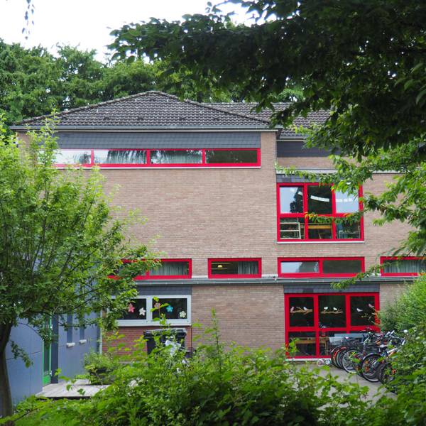Ein Schulgebäude, davor Fahrräder und Bäume.