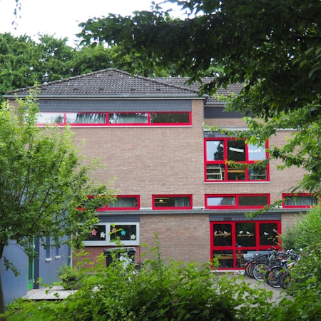 Ein Schulgebäude, davor Fahrräder und Bäume.