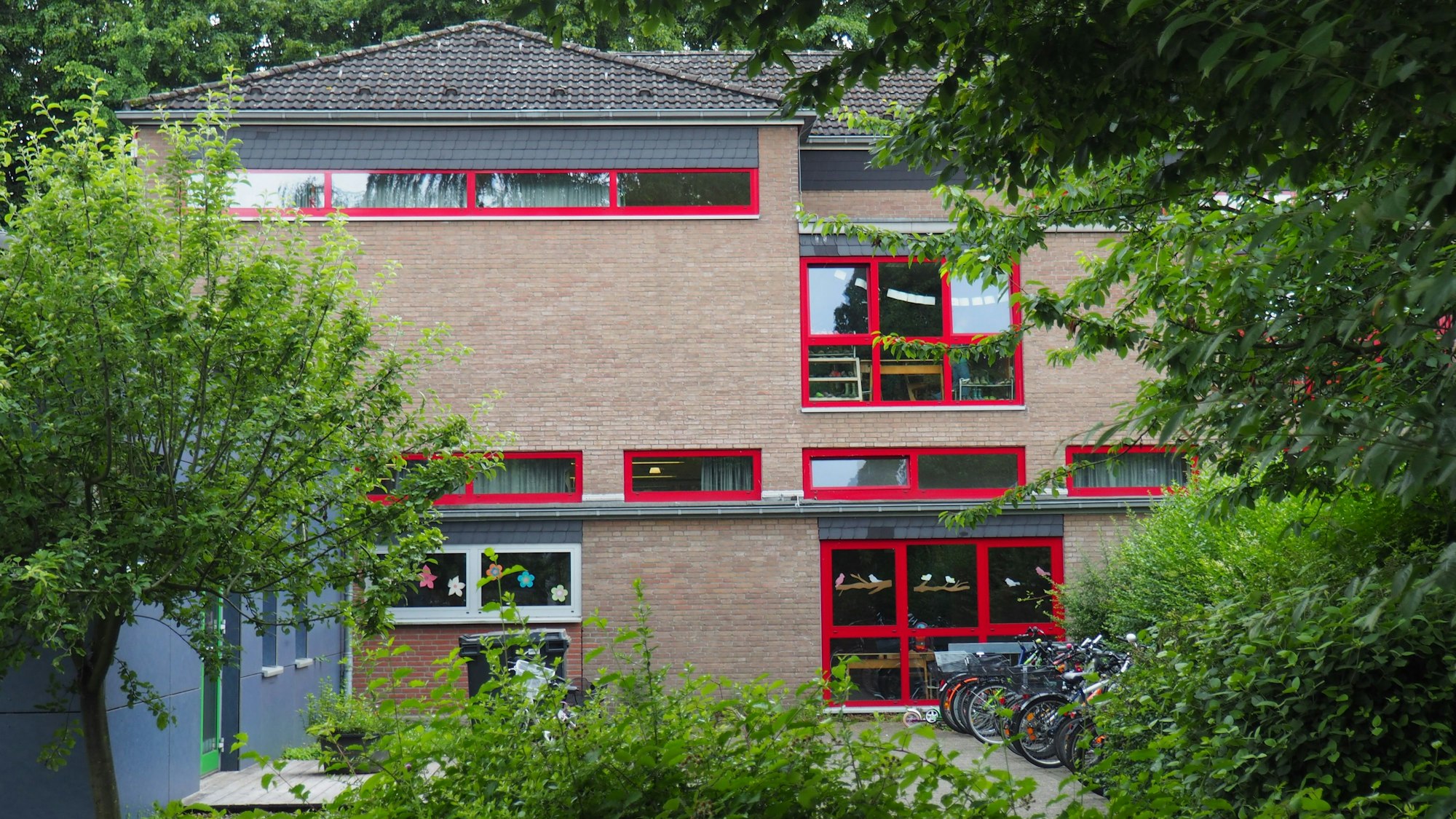 Ein Schulgebäude, davor Fahrräder und Bäume.