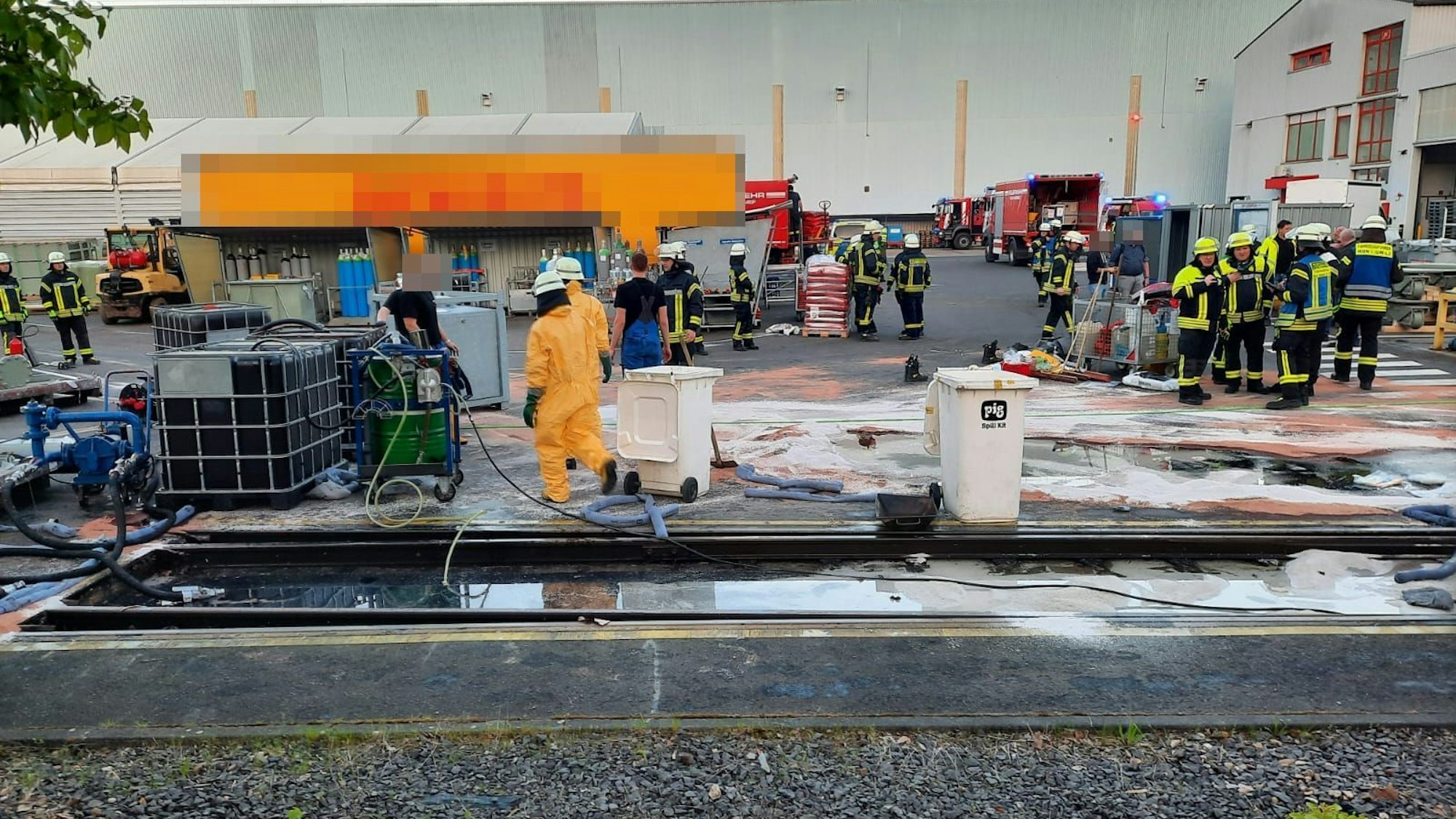 Viele Feuerwehrleute stehen auf einem Firmengelände.