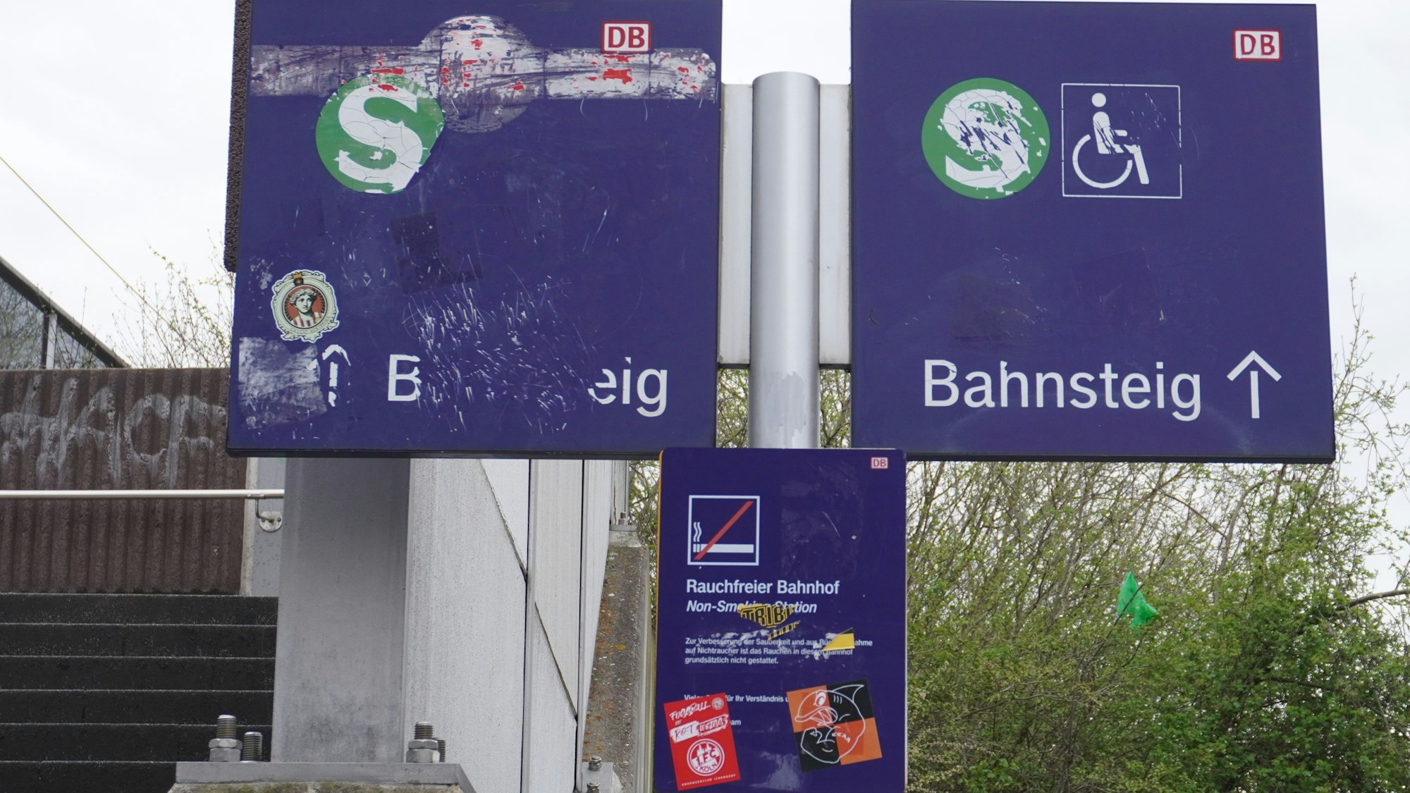 Das Bild zeigt Hinweisschilder der Deutschen Bahn, die verkratzt oder verklebt sind.