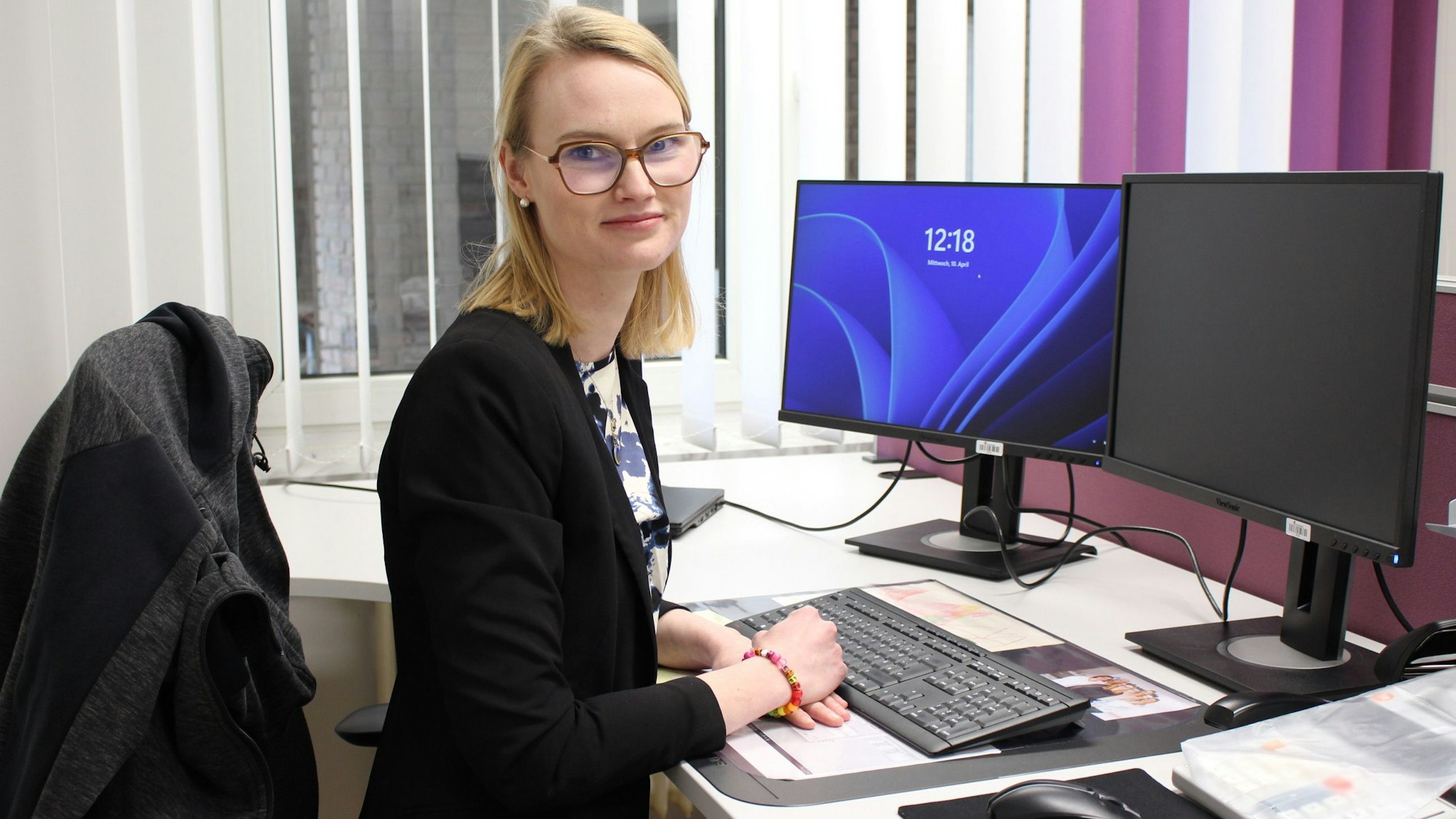 Elfi Frauenkron sitzt an ihrem Schreibtisch, vor ihr stehen Tastatur und Bildschirme.