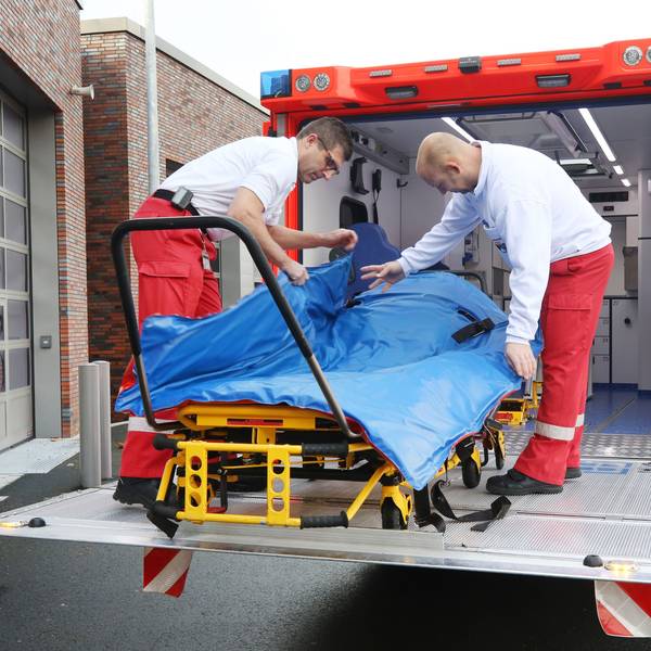 Mit einer Schwerlasttrage hantieren die Feuerwehrleute Oliver Schwarz (l) und Marc Elmhorst auf der Hebebühne des Schwerlastrettungswagens.
