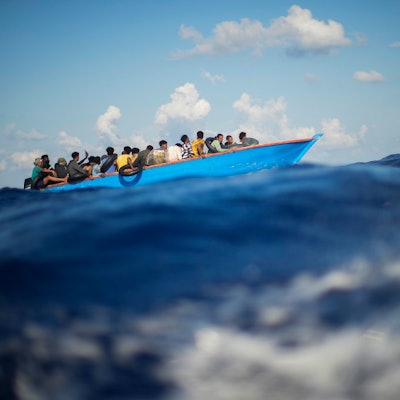 Migranten sitzen in einem Boot auf dem Meer.