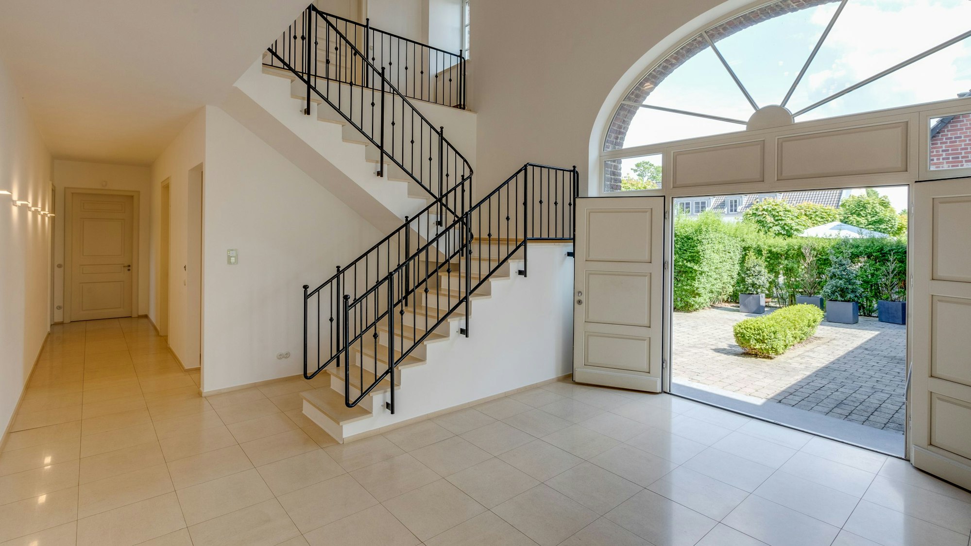 Blick aus dem Foyer des Sophienhof Richtung Treppenhaus und Eingangsbereich mit Flügeltür.