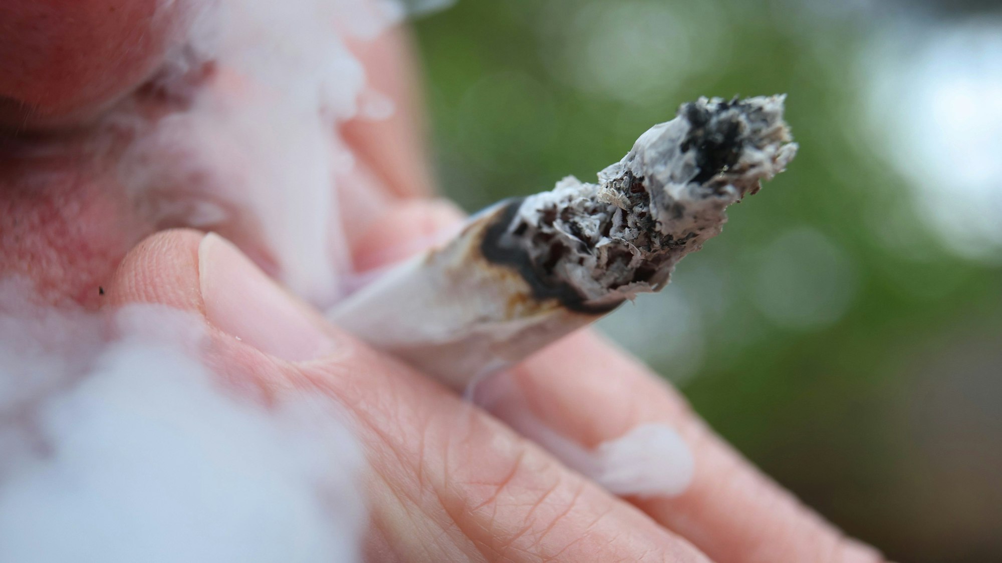 Ein Mann raucht einen Joint.