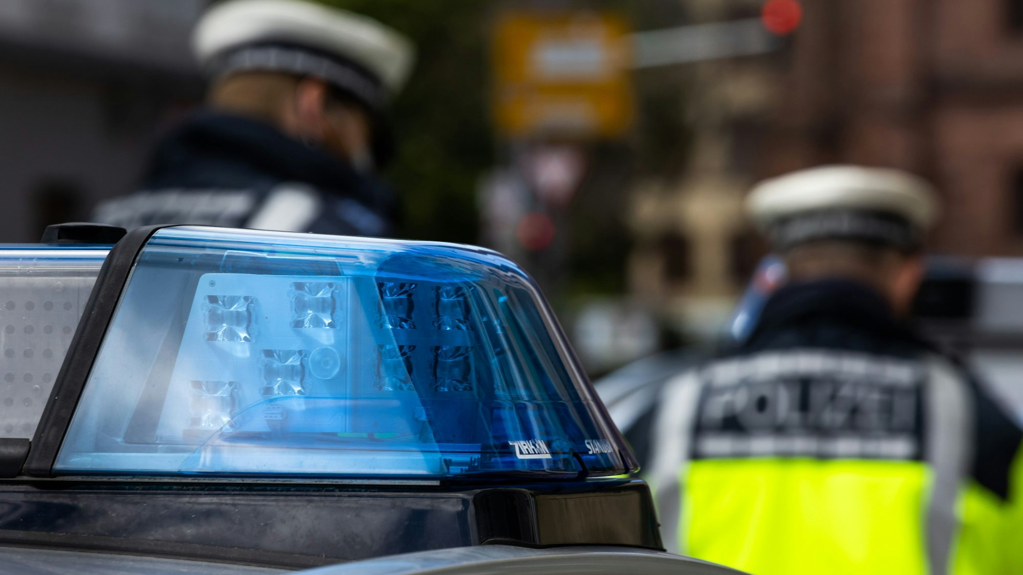 Zwei Polizeibeamte stehen zwischen zwei Einsatzfahrzeugen der Polizei.