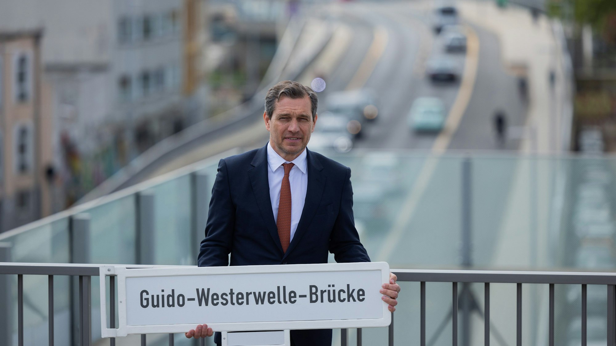 Michael Mronz, Ehemann von Guido Westerwelle und Witwer, hält das Schild mit dem neuen Namen der Brücke.