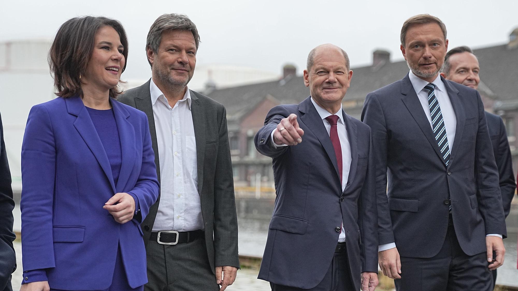 Annalena Baerbock, Robert Habeck, Olaf Scholz, und Christian Lindner gehen auf einer Straße.