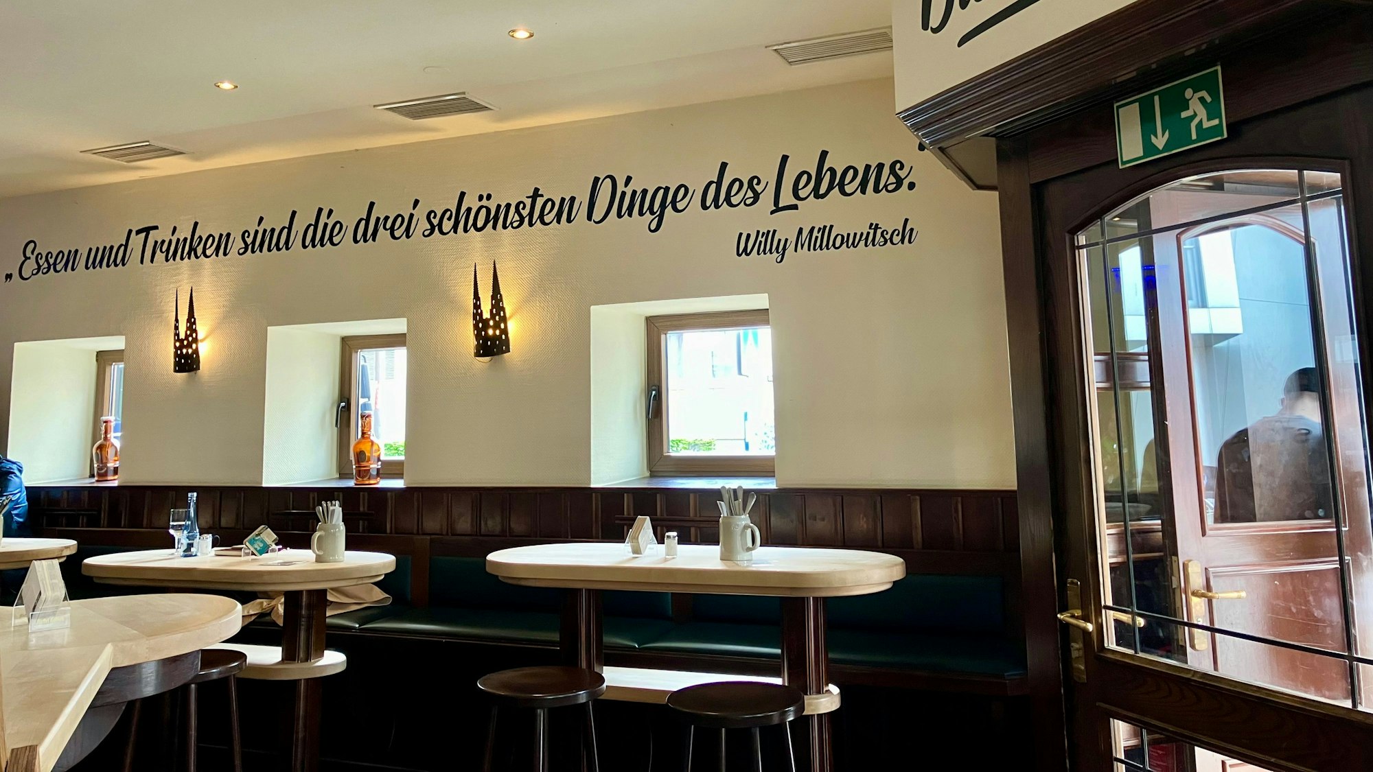 Der Innenraum des Bayenthaler Wirtshaus. An der Wand ist ein Zitat von Willy Millowitsch niedergeschrieben: „Essen und Trinken sind die drei schönsten Dinge des Lebens.“ Foto von Elena Stickelmann