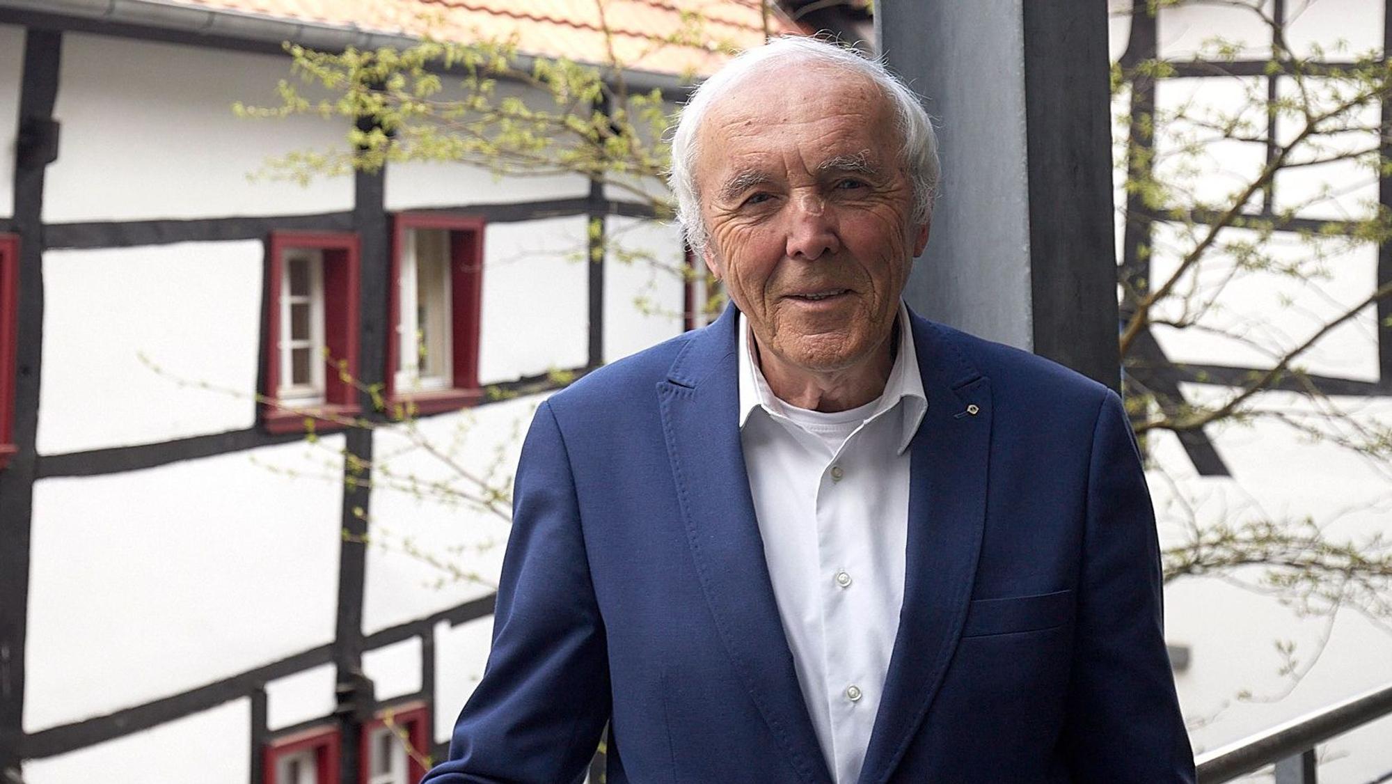 Das Bild zeigt Frank Günter Zehnder. Im Hintergrund sind Fachwerkhäuser zu sehen.
