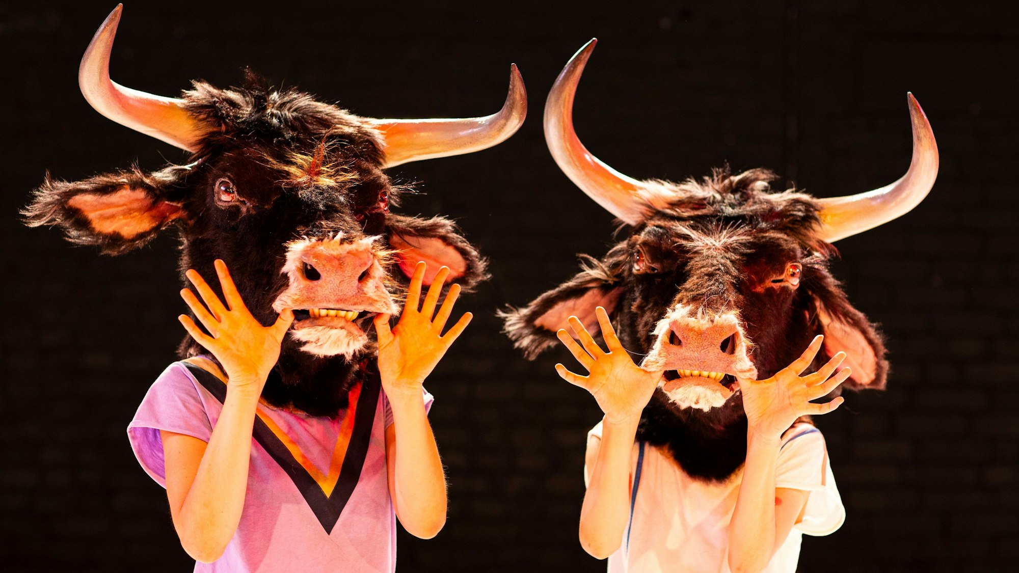 Zwei Tänzerinnen tragen lebensechte Auerochsenmasken.