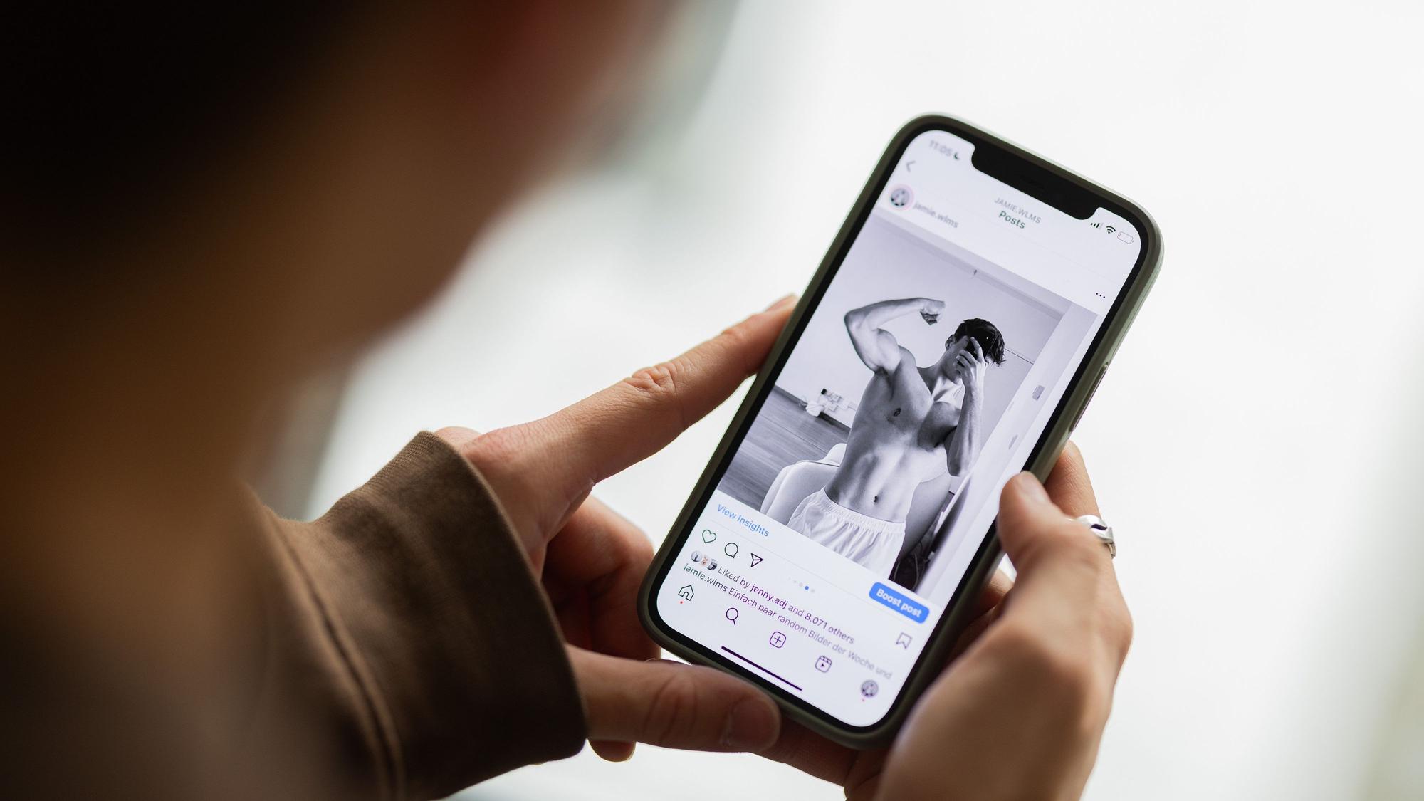 Jamie Williams zeigt ein Foto von sich auf seinem Smartphone.