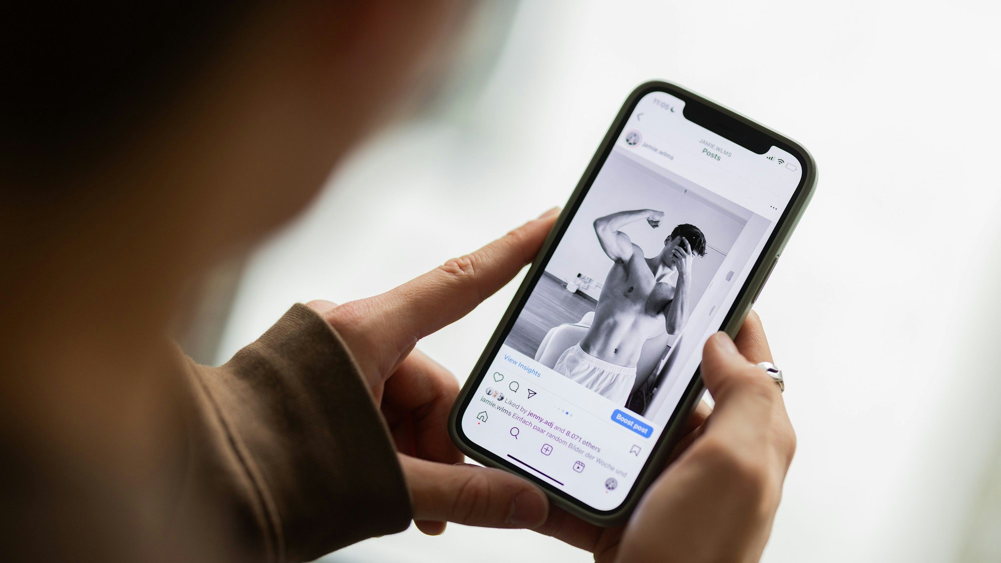 Jamie Williams zeigt ein Foto von sich auf seinem Smartphone.